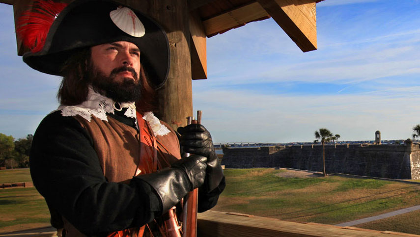 Man in colonial clothing in a high viewpoint. Looking out to the stone walls